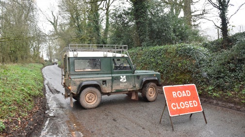 A red 'road closed' sign and a Landrover blocking the road